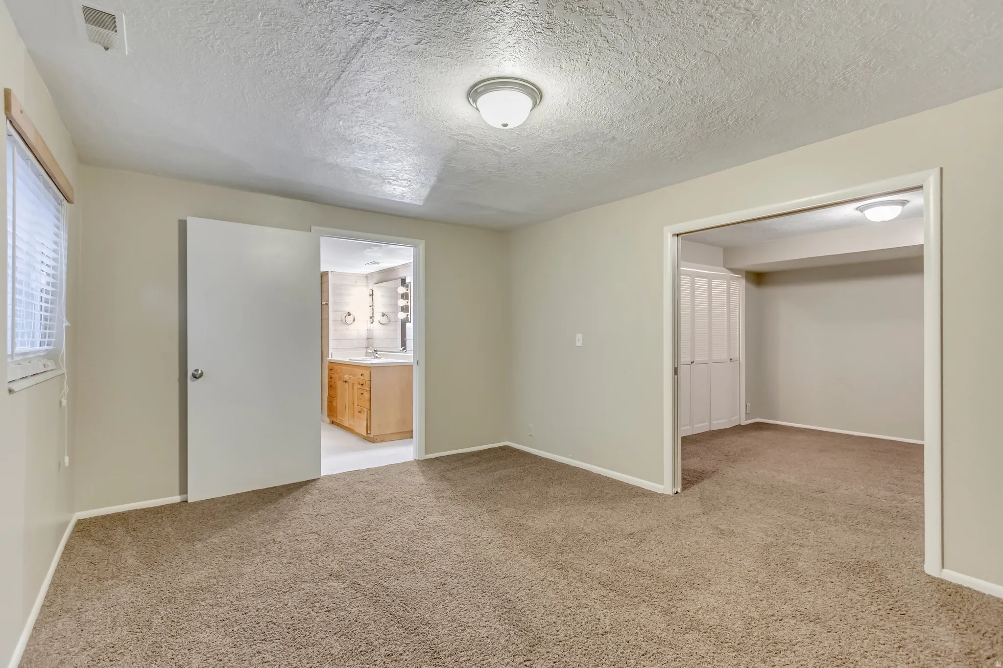 Unfurnished bedroom featuring a textured ceiling and light carpet
