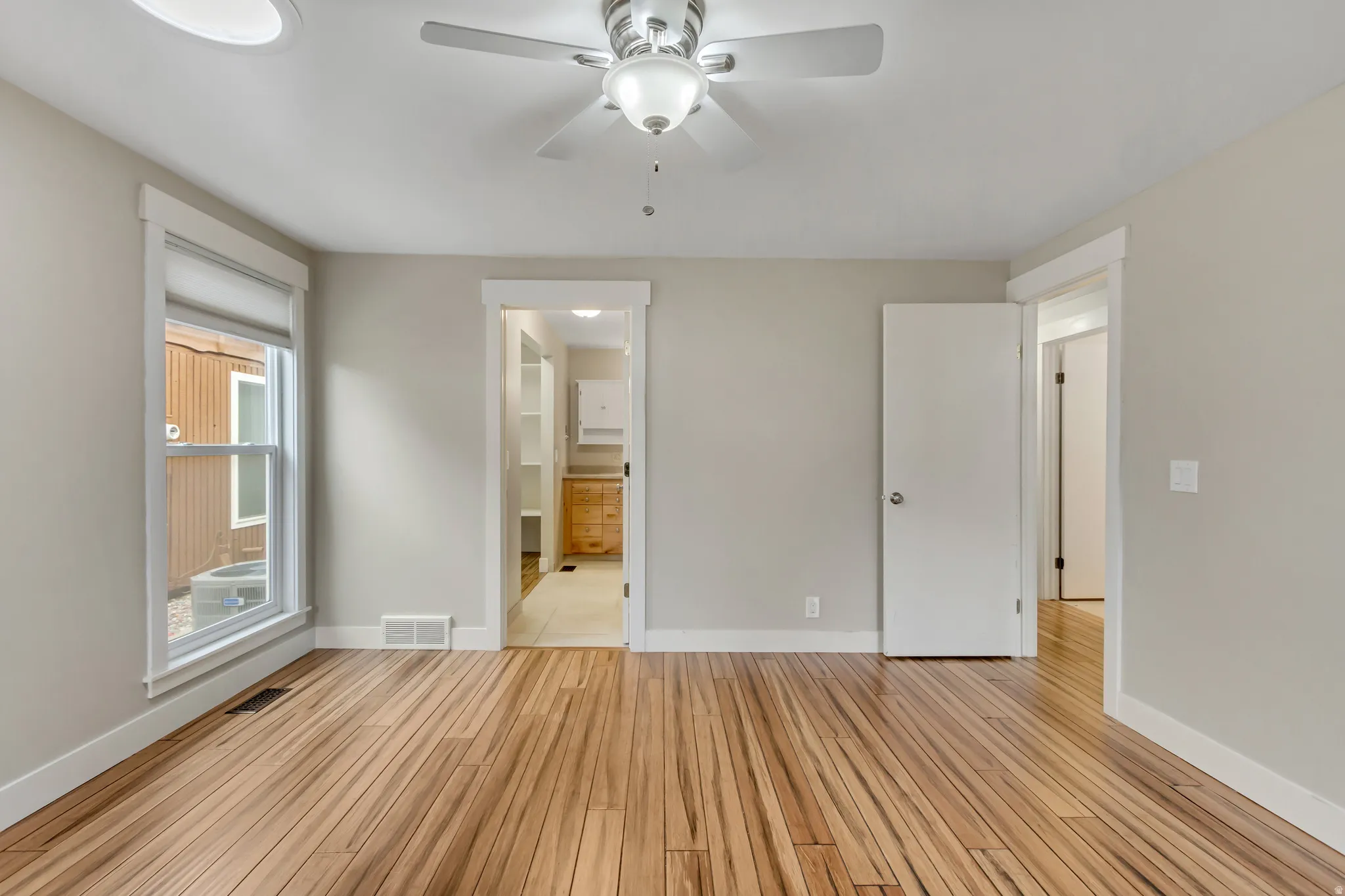 Unfurnished bedroom featuring a ceiling fan, light wood finished floors, and ensuite bathroom