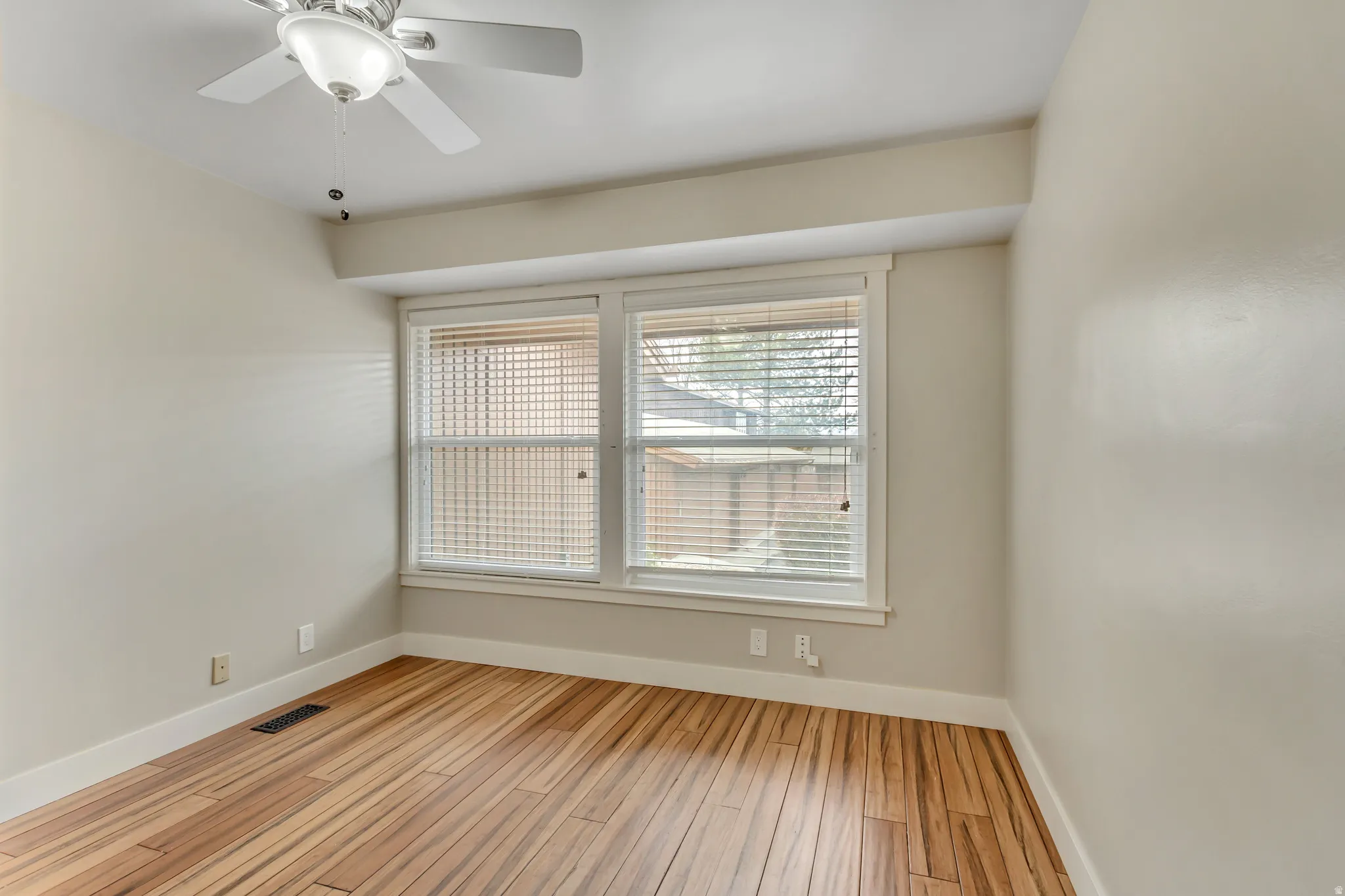 Bedroom 2 with light wood finished floors and a ceiling fan