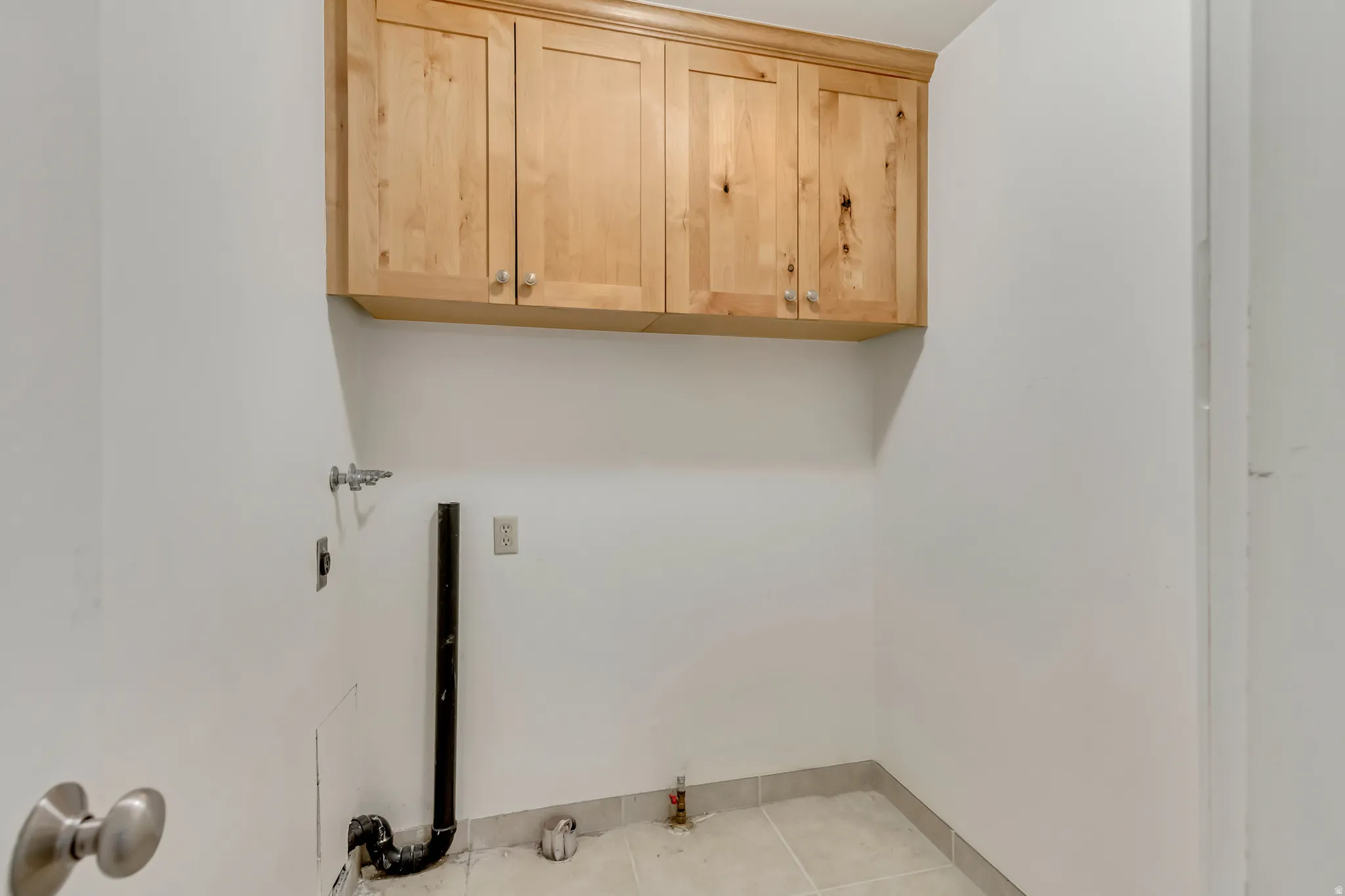 Laundry area with cabinet space, light tile patterned floors, and washer/dryer hookup