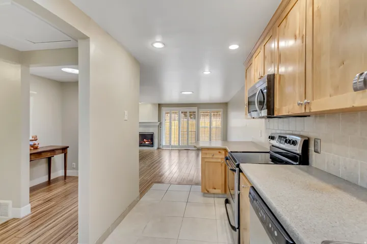 Kitchen featuring appliances with stainless steel finishes, light brown cabinets, backsplash, and light tile patterned floors.