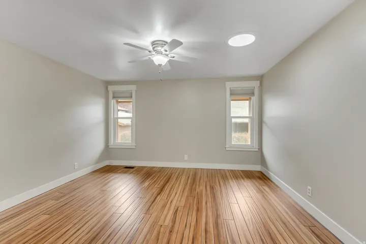 Empty room featuring healthy amount of natural light, light wood-type flooring, and ceiling fan