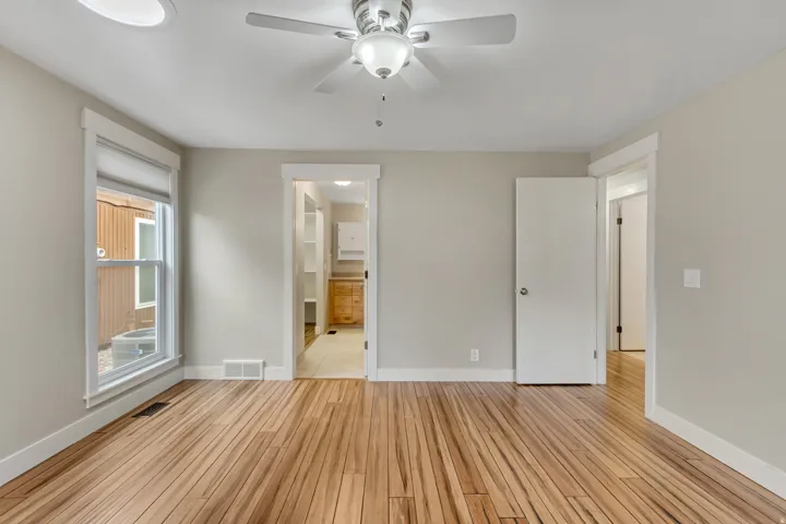 Unfurnished bedroom featuring a ceiling fan, light wood finished floors, and ensuite bathroom