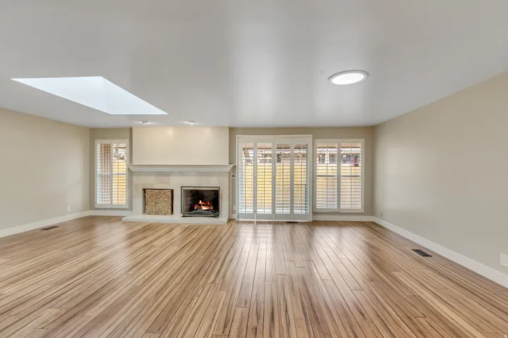 Unfurnished living room featuring a skylight, light wood-type flooring, healthy amount of natural light, and a tiled fireplace