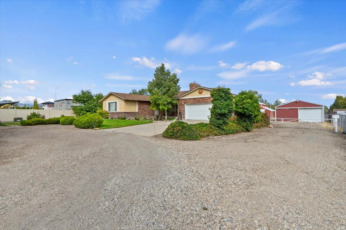 View of front of property featuring a garage, a chimney, and driveway