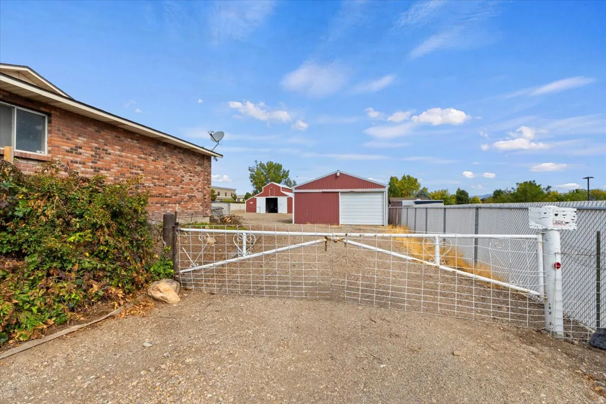 View of yard featuring a gate, an outdoor structure, a detached garage, and an outbuilding