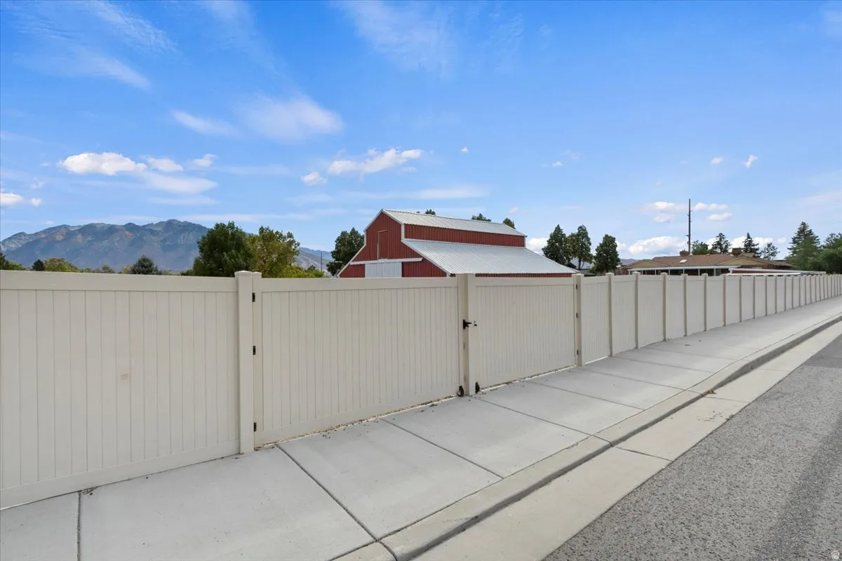 View of asphalt road with a gate, a mountain view, sidewalks, and curbs