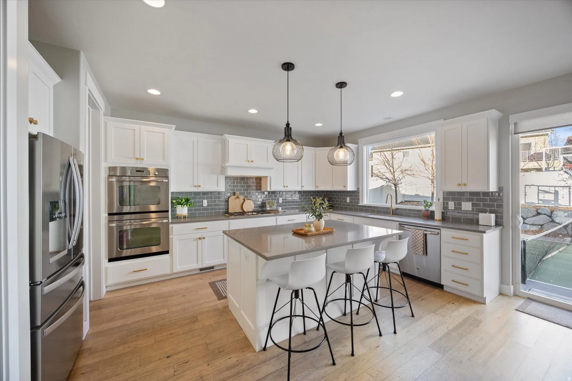 Beautiful kitchen featuring white cabinets, quartz countertops, double ovens, built in microwave and large pantry