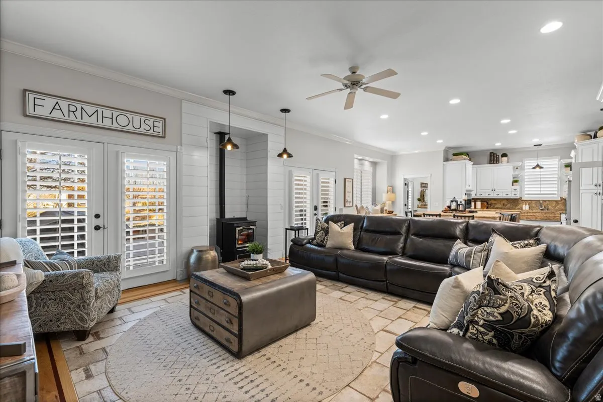 Living area featuring french doors, ornamental molding, a wood stove, a ceiling fan, and recessed lighting