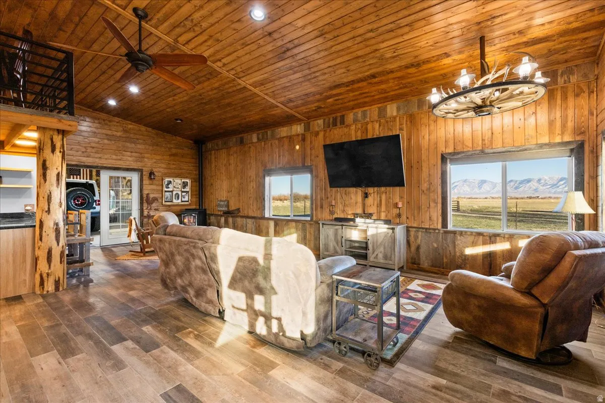 Living room with wood ceiling, healthy amount of natural light, dark wood finished floors, vaulted ceiling, and wood walls