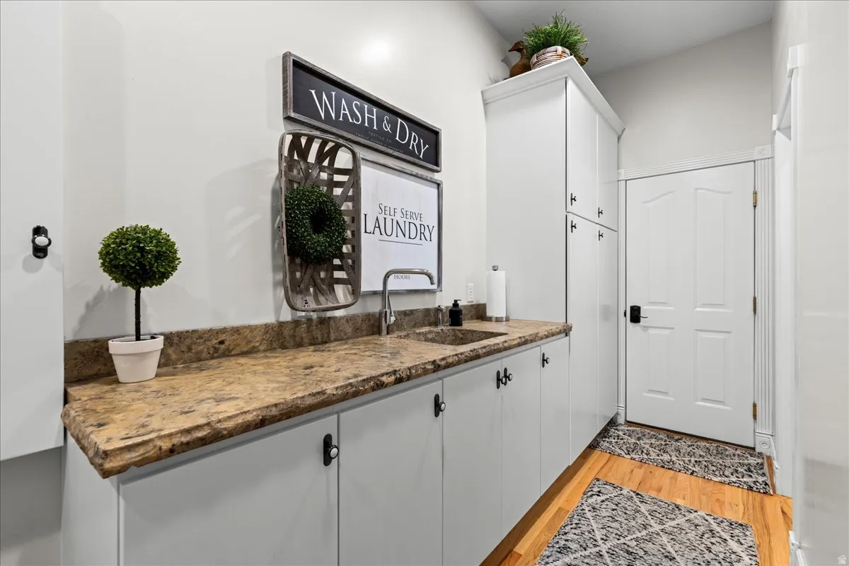 Bar area featuring dark stone countertops, light wood-style floors, and white cabinetry