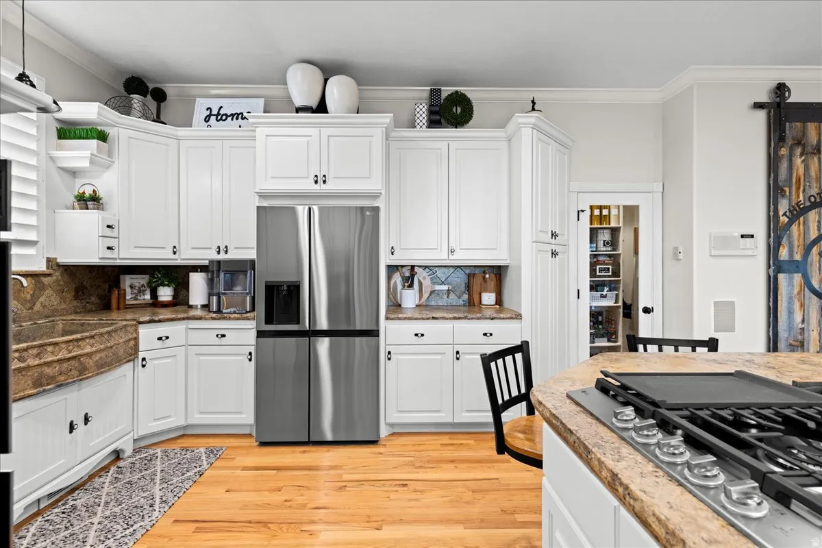 Kitchen featuring ornamental molding, stainless steel appliances, white cabinets, open shelves, and light wood-style floors
