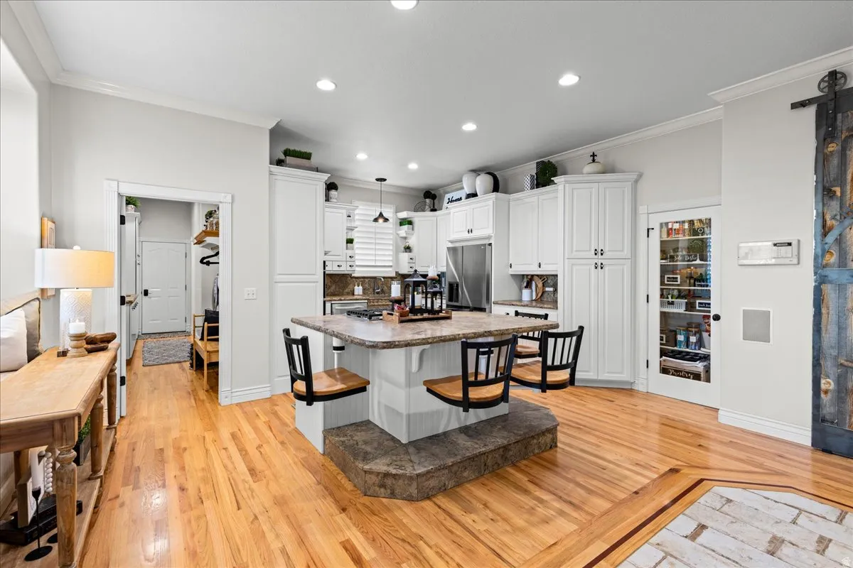 Kitchen with crown molding, white cabinets, a breakfast bar, a kitchen island, and recessed lighting