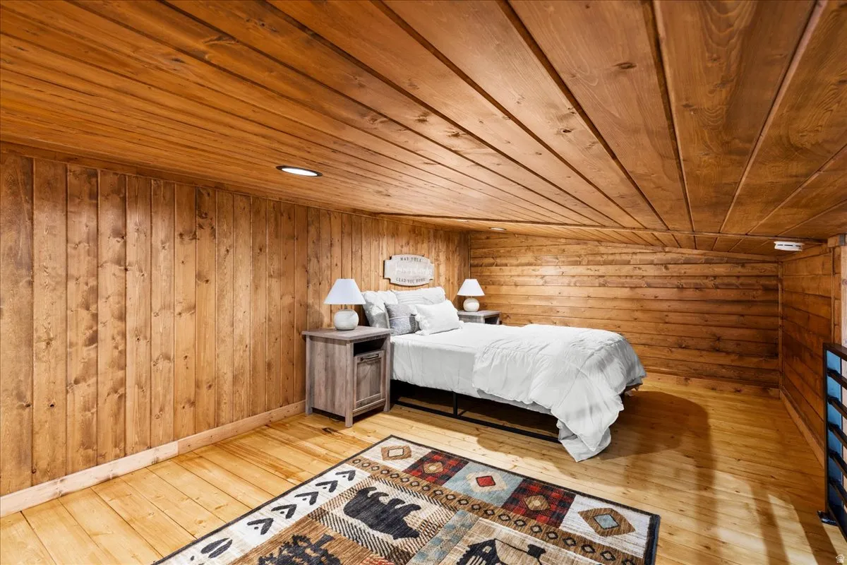 Bedroom featuring wood ceiling, wood walls, and light wood-style floors