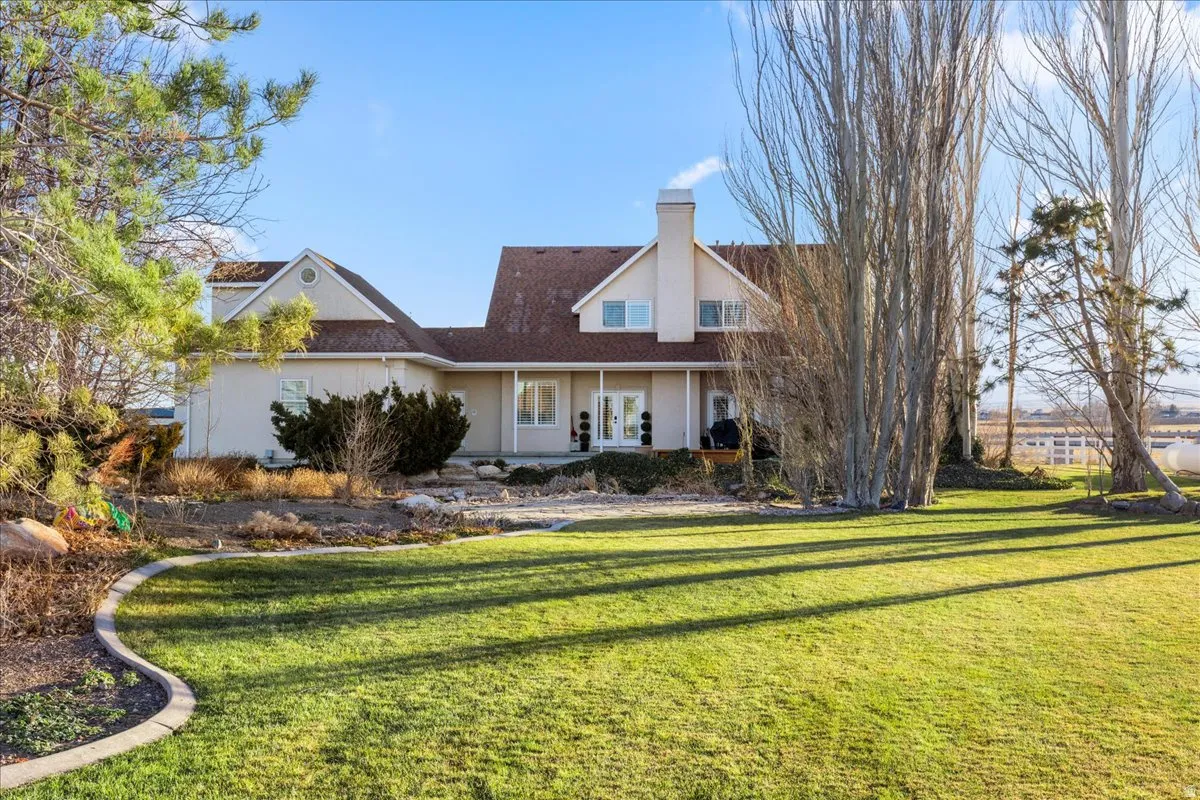 View of front of home with a front yard, a chimney, and stucco siding