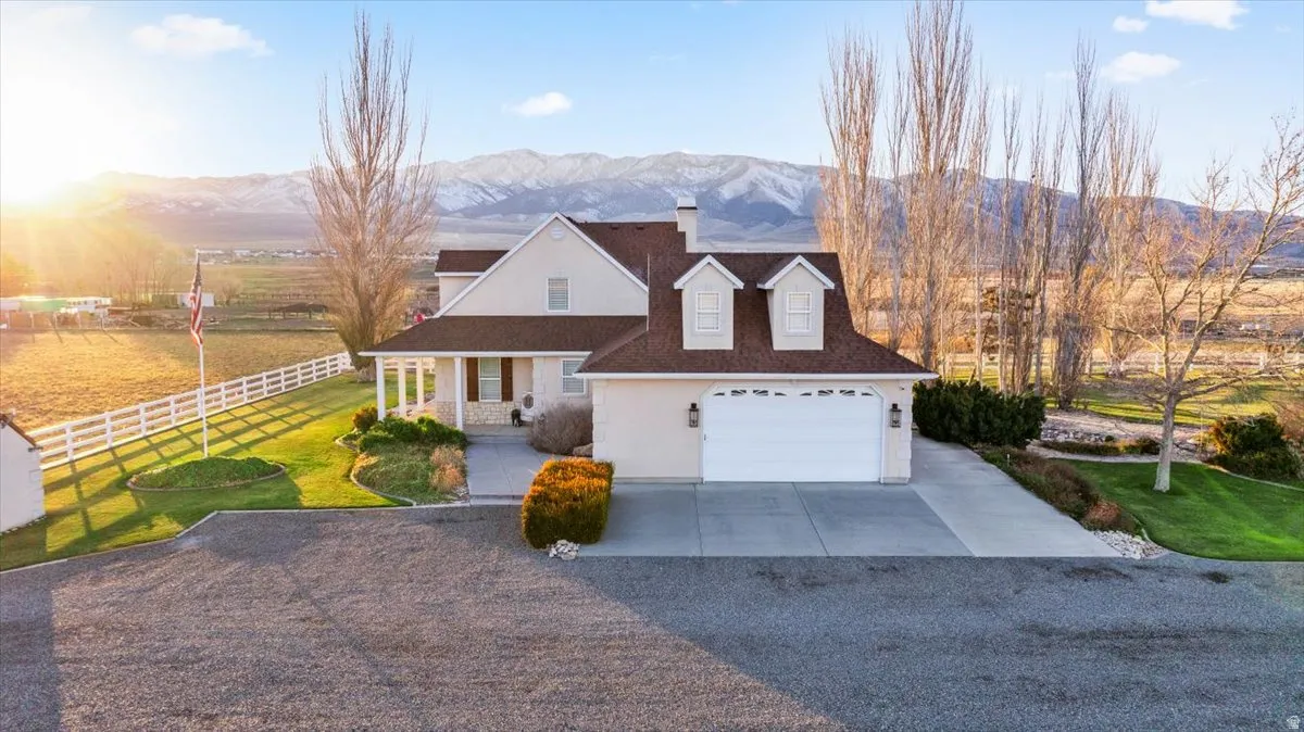 View of front facade featuring covered porch, a mountain view, concrete driveway, a garage, and a chimney