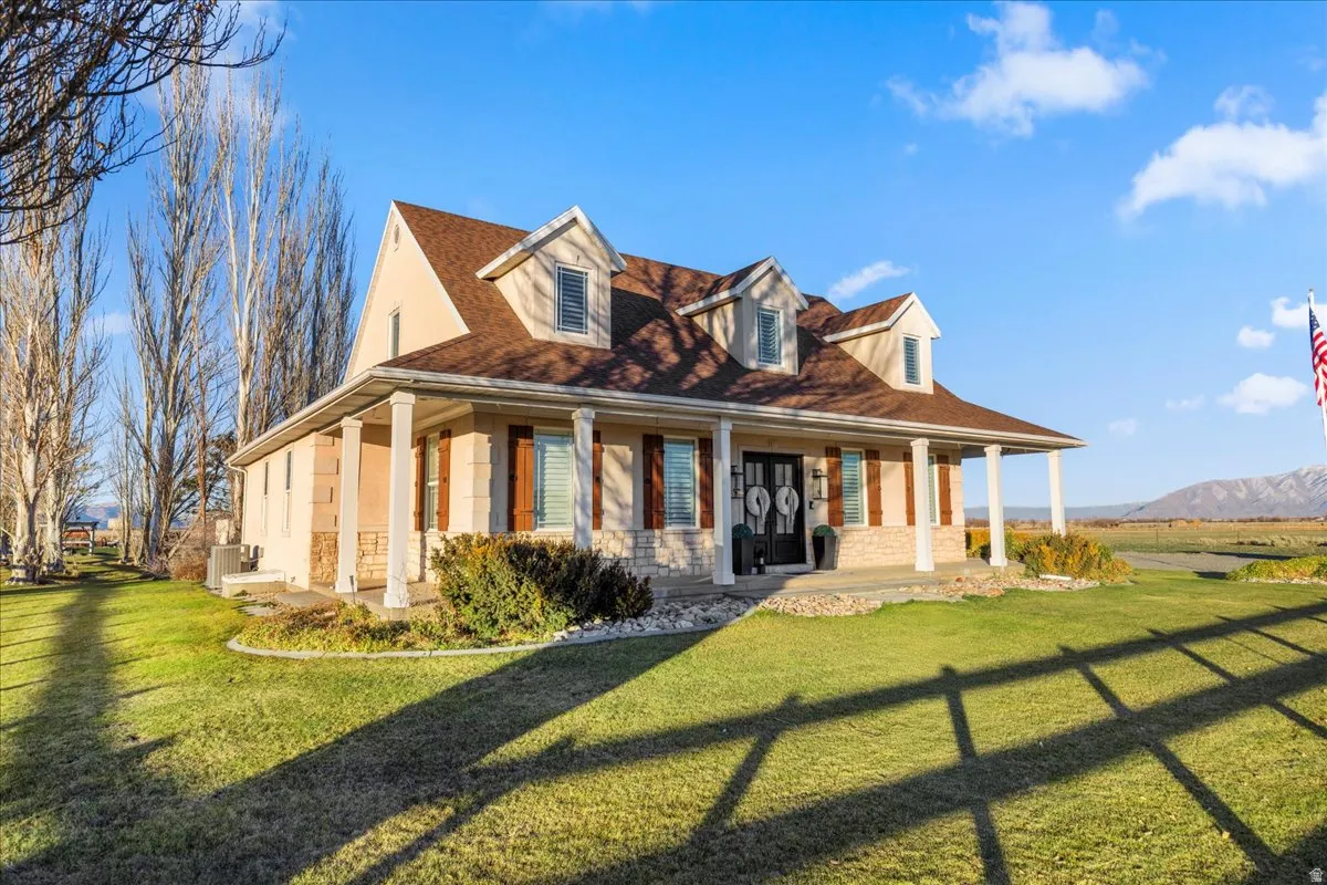Rear view of property featuring a porch, a lawn, stucco siding, and stone siding