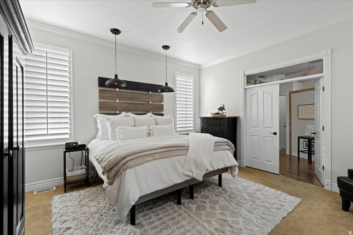 Bedroom featuring ornamental molding, light carpet, and ceiling fan