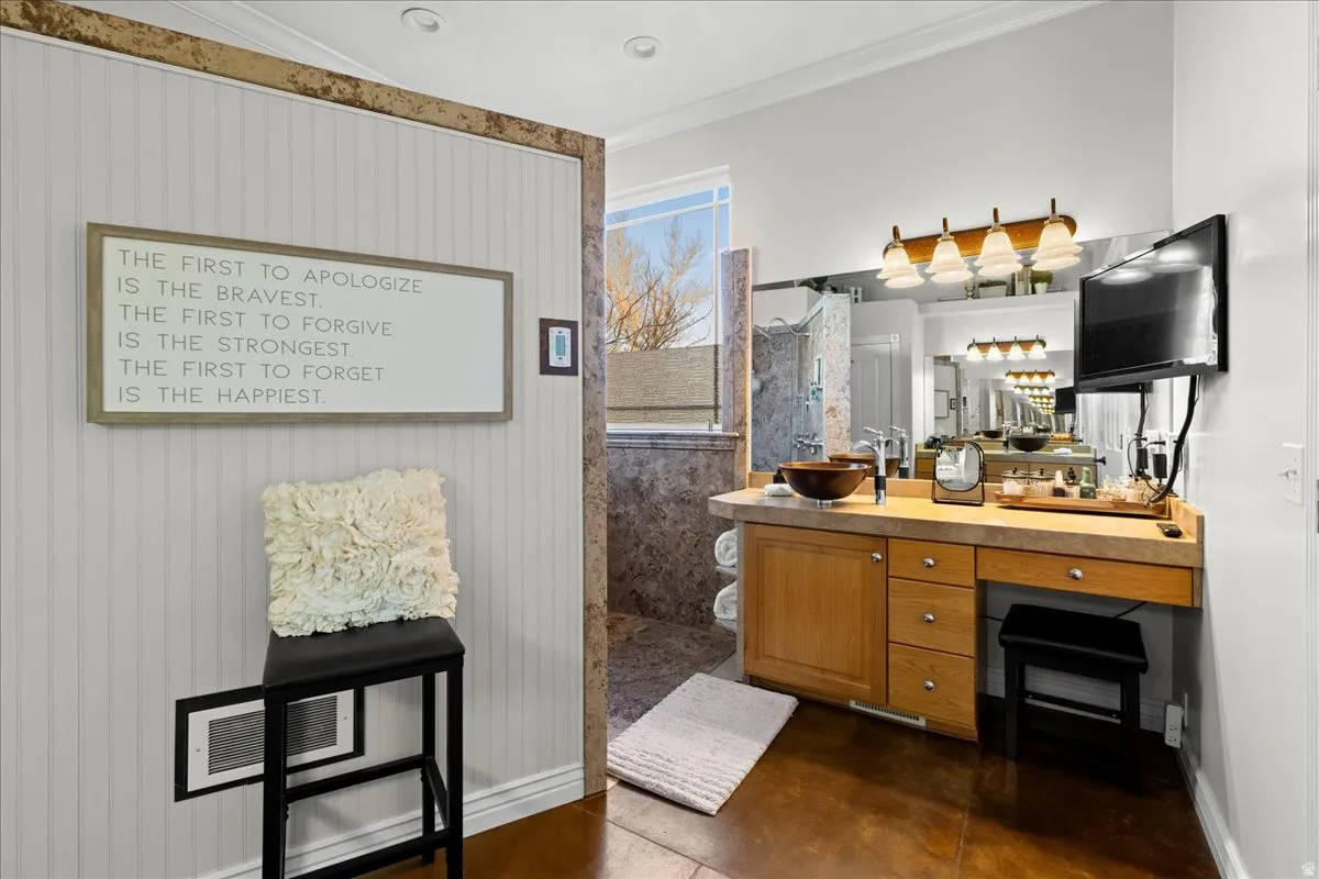 Bathroom featuring finished concrete flooring, ornamental molding, vanity, and a walk in shower