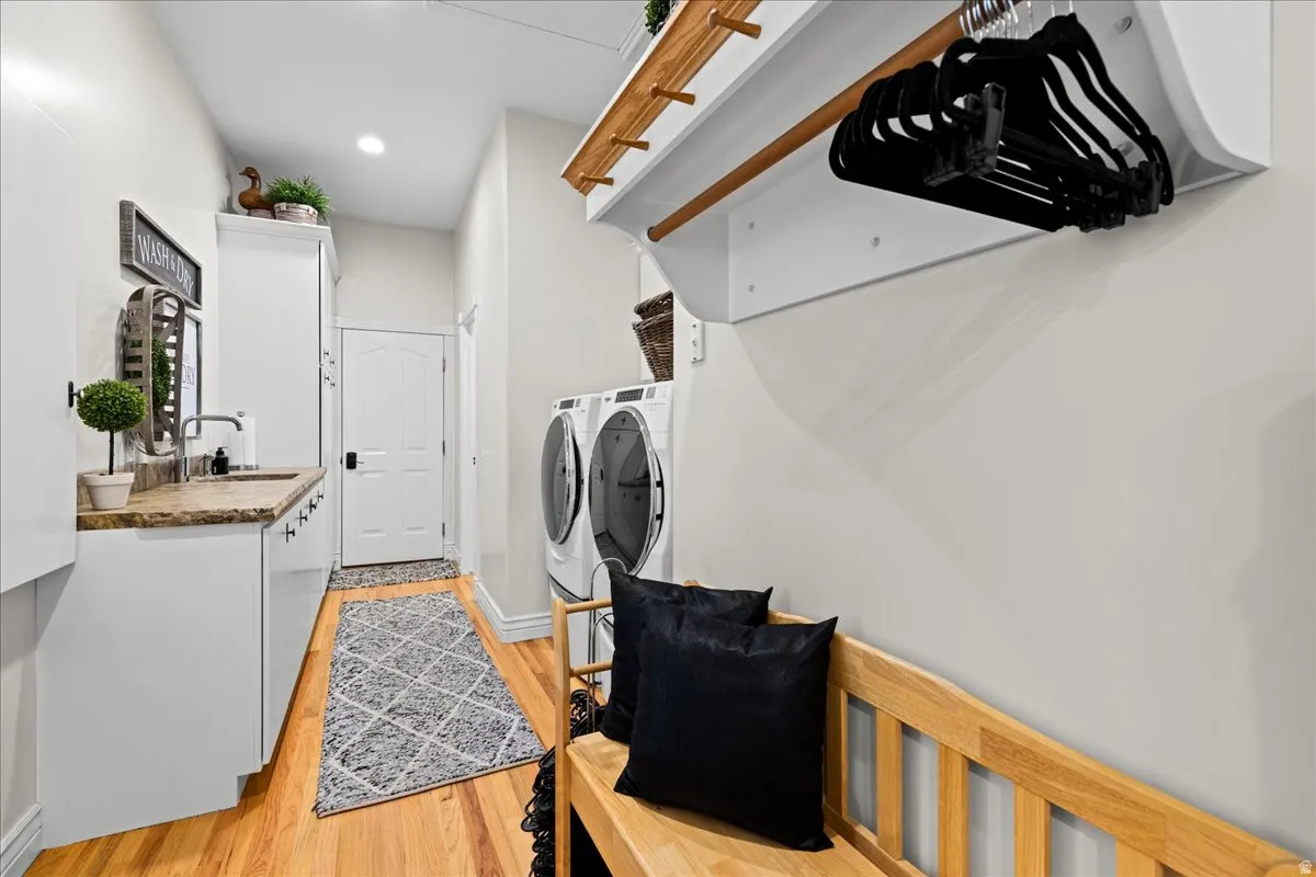 Laundry area with washing machine and clothes dryer, light wood-type flooring, recessed lighting, and cabinet space