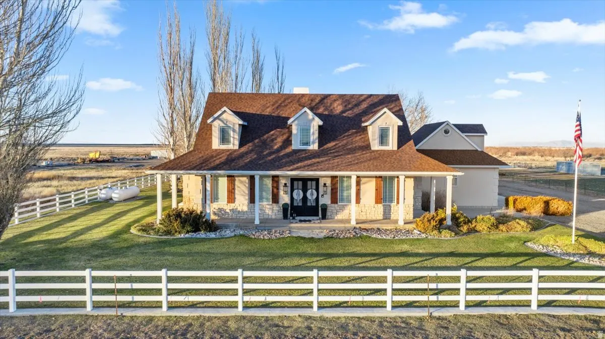 View of front facade featuring covered porch, a fenced front yard, and stone siding