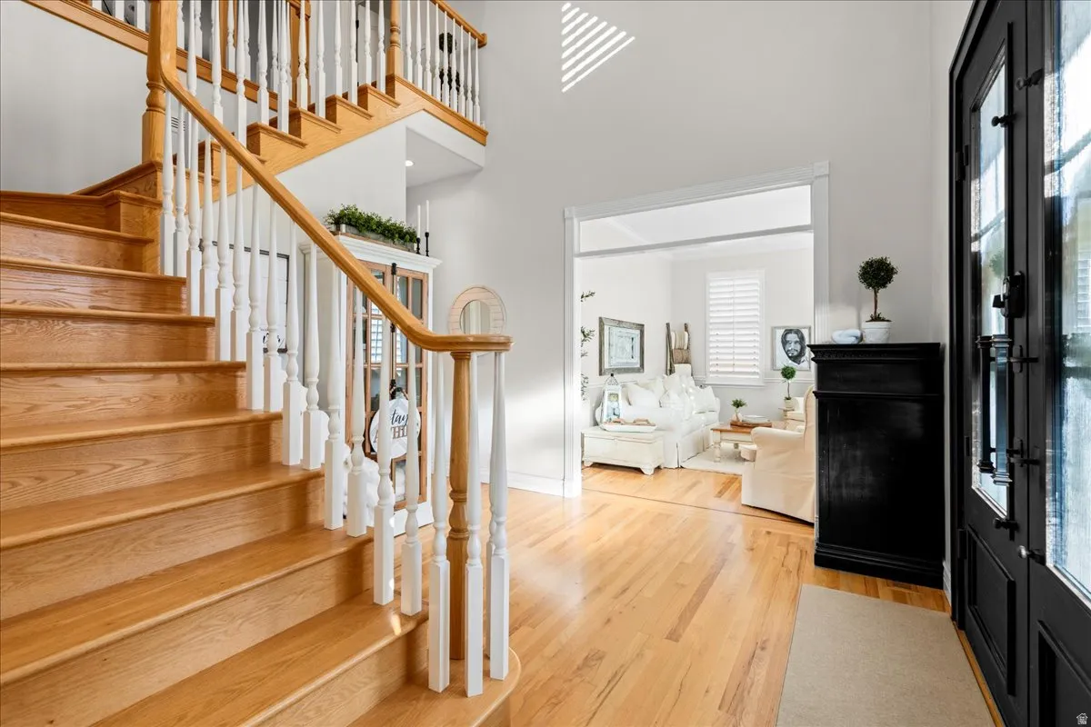 Entryway featuring light wood-type flooring, stairway, and a towering ceiling