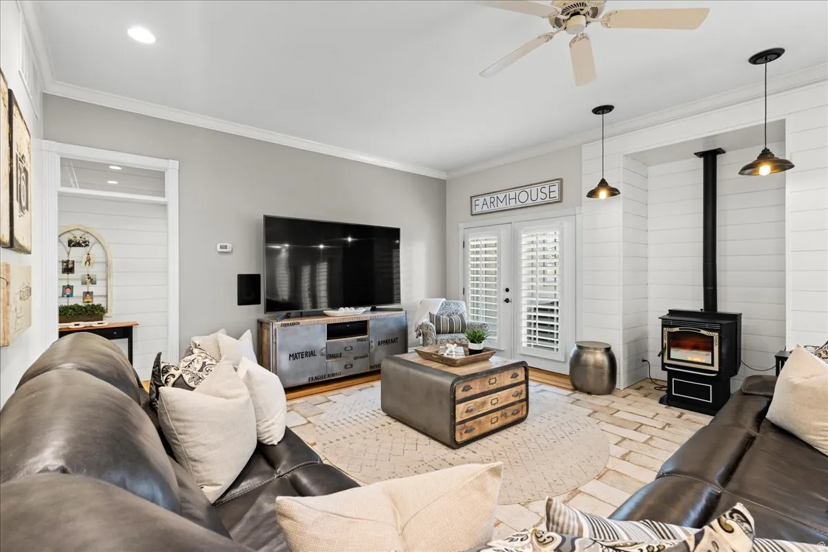 Living area featuring a wood stove, crown molding, and a ceiling fan