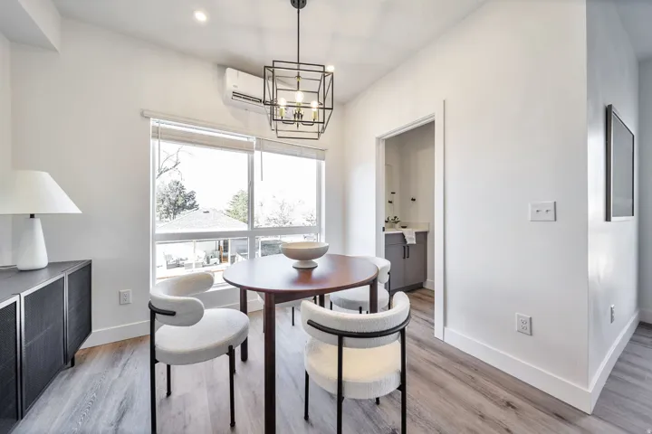 Dining room featuring a wall unit AC, light wood finished floors, and a chandelier