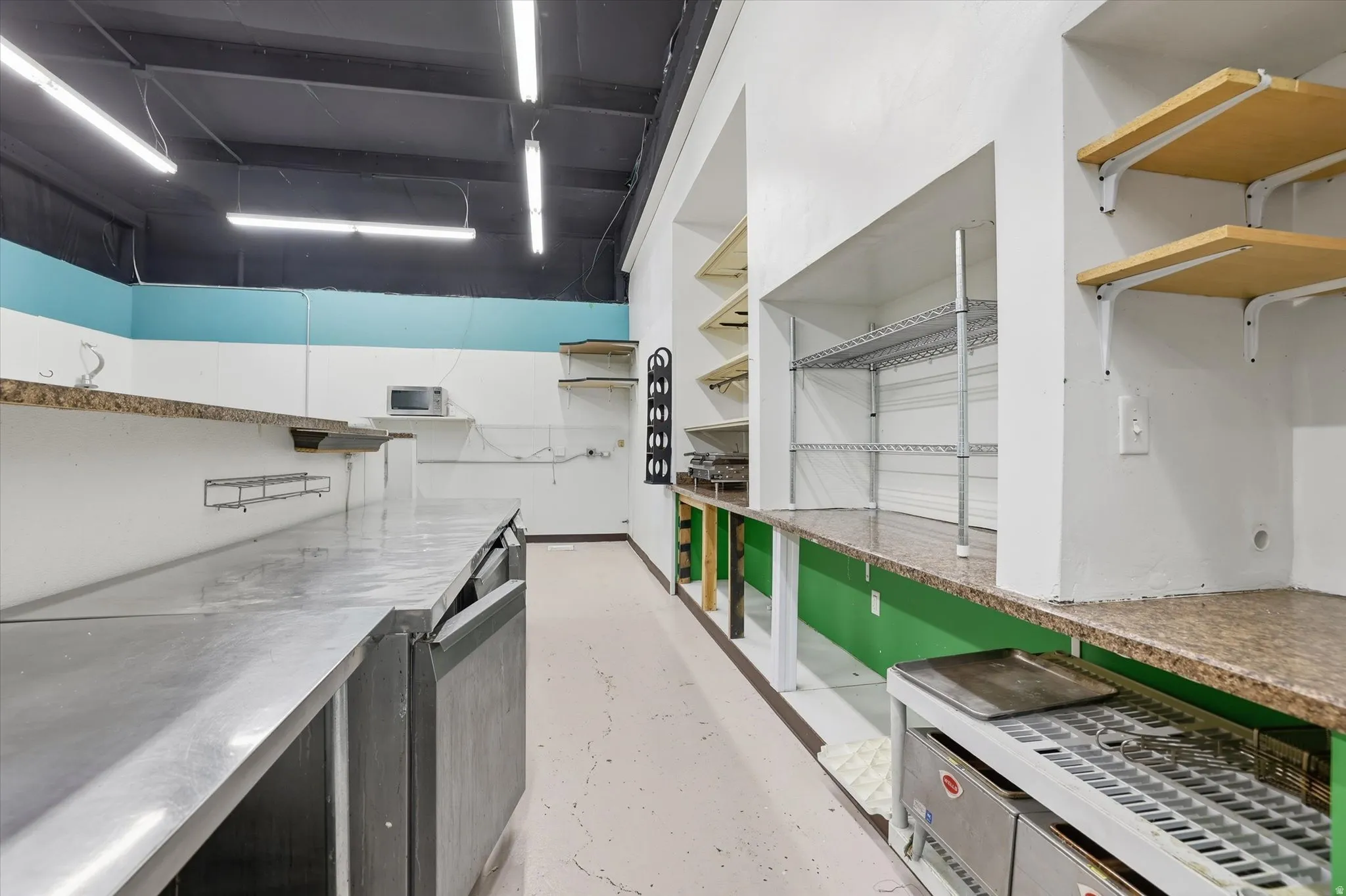 Kitchen featuring stainless steel counters and unfinished concrete flooring
