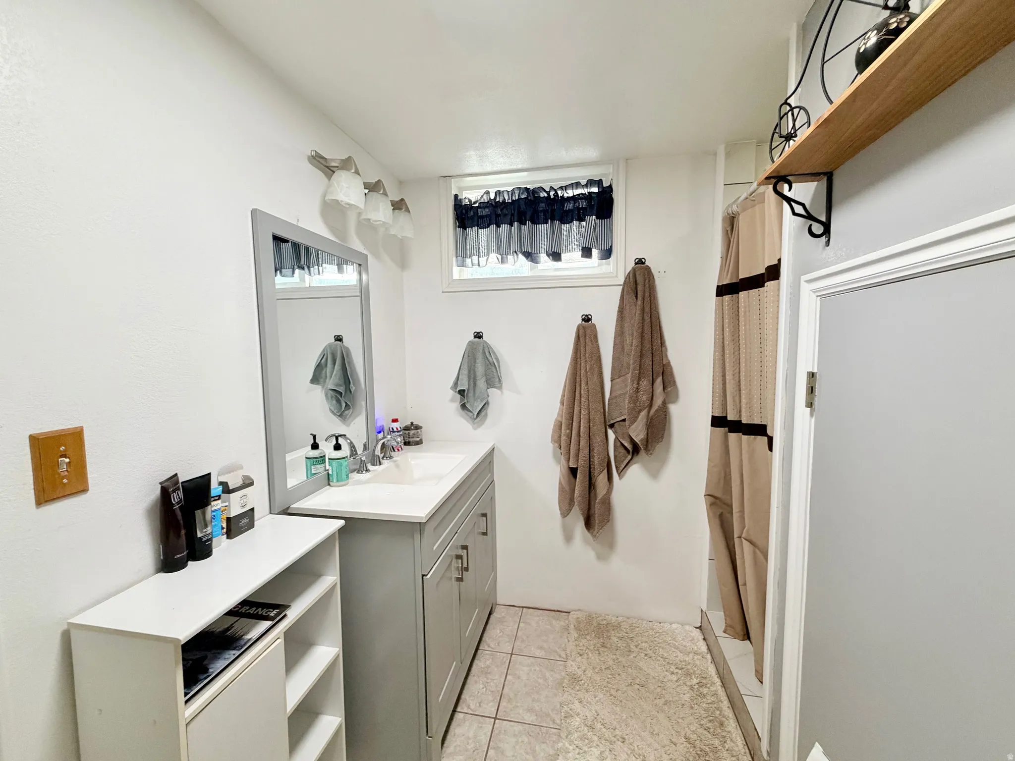 3/4 bath with a shower with curtain, vanity, and light tile patterned floors