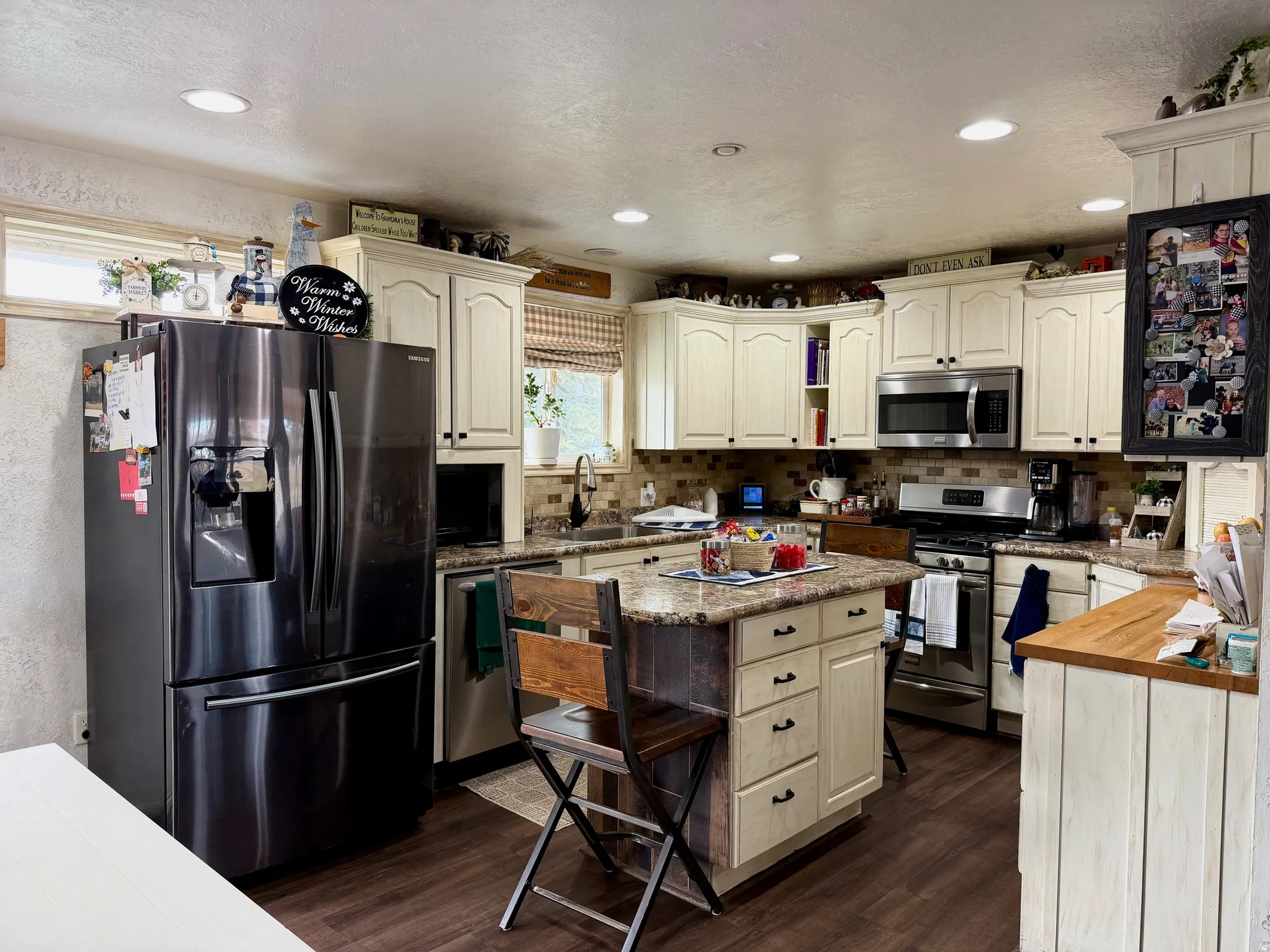 Kitchen featuring appliances with stainless steel finishes, a textured wall, a kitchen island, a breakfast bar, and light counters