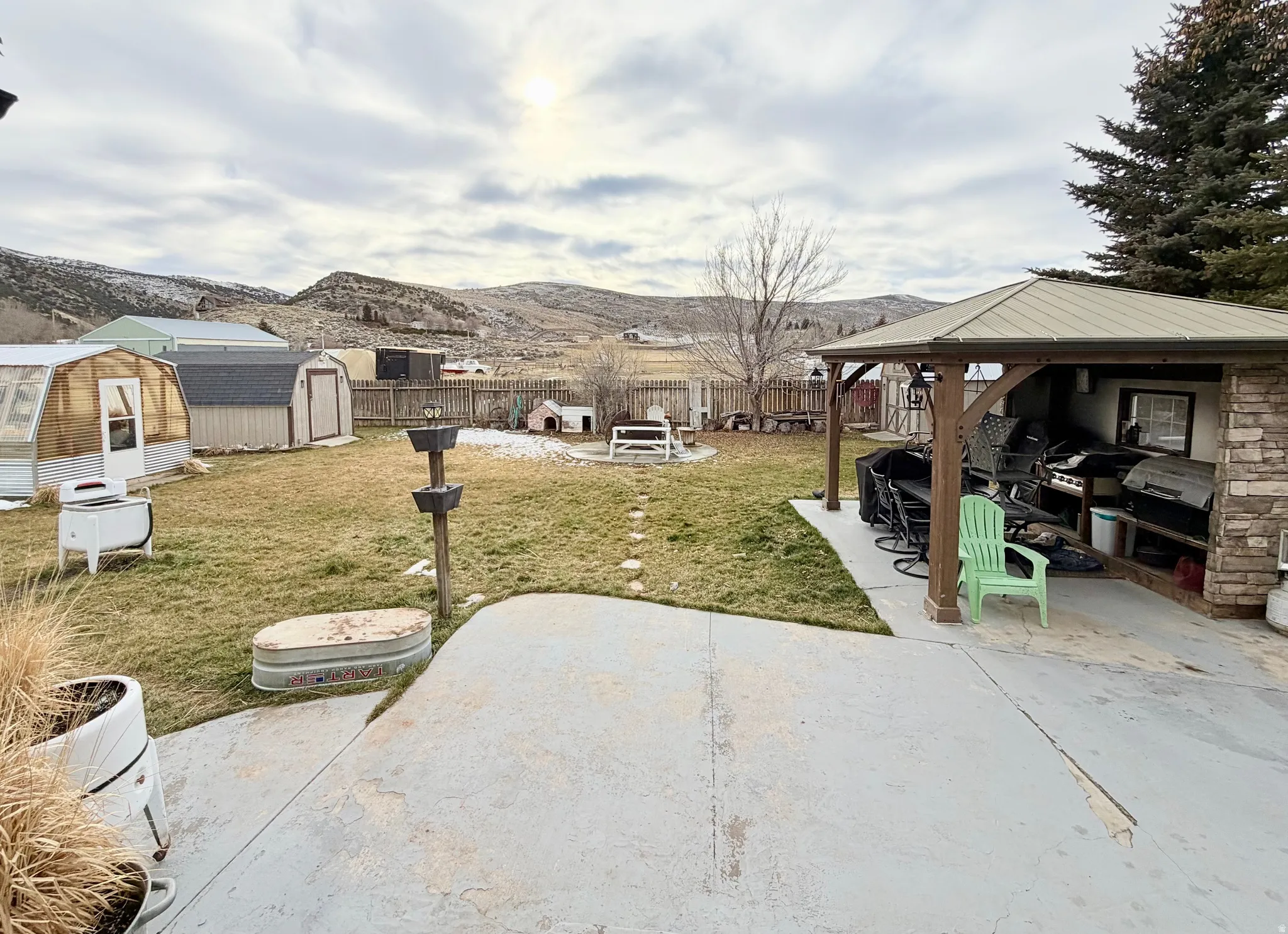 Fenced backyard featuring a gazebo, a patio area, a storage unit, and a mountain view