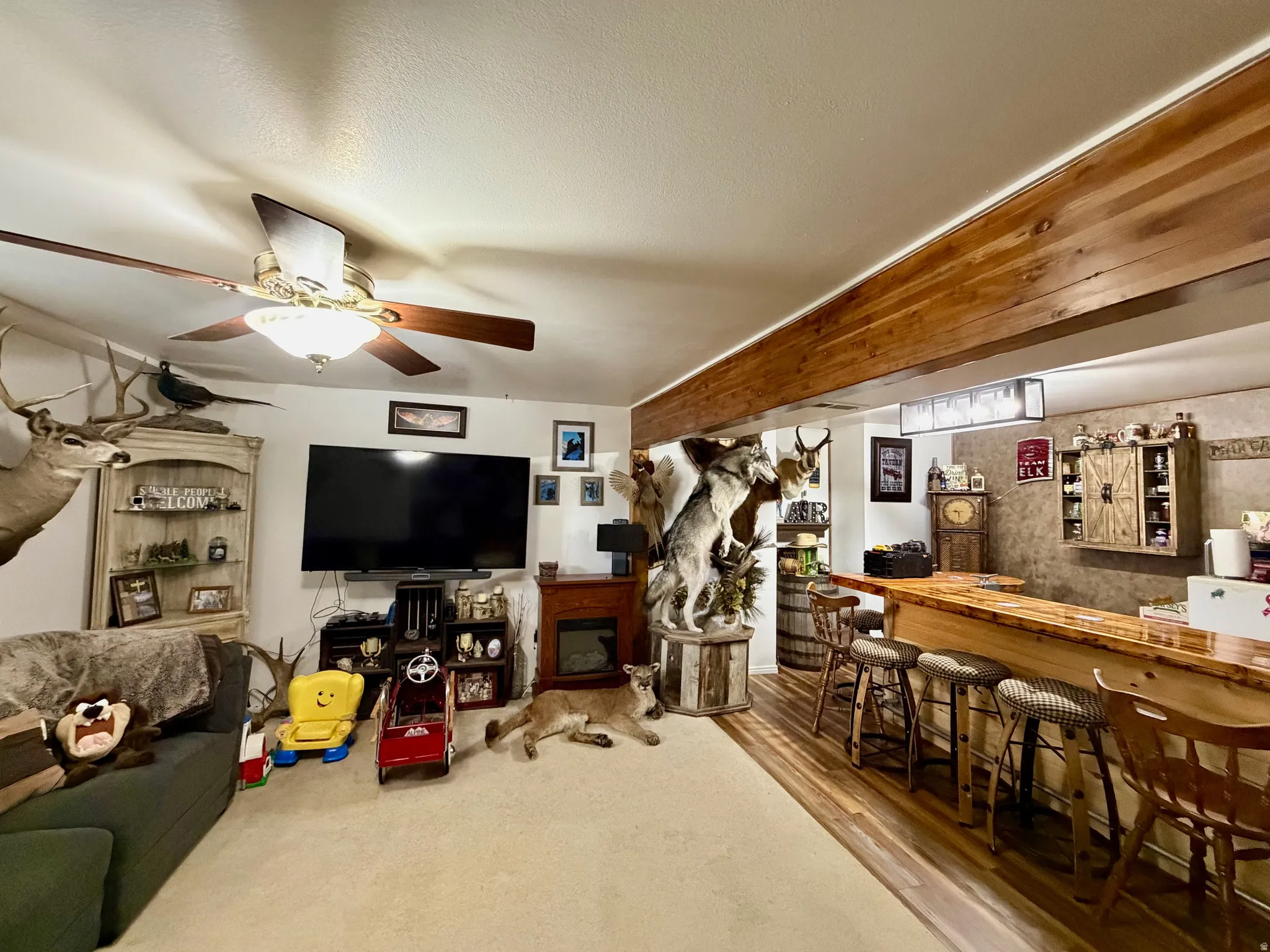 Living area featuring a bar, wood finished floors, a ceiling fan, and a textured ceiling