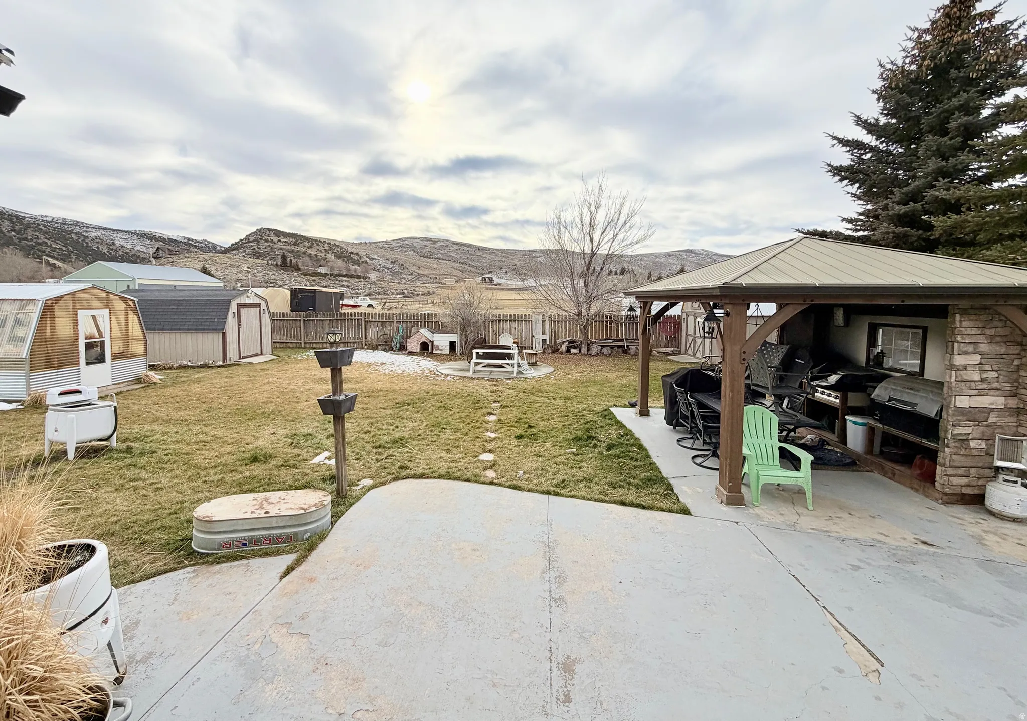 Fenced backyard featuring a patio area, a gazebo, a storage shed, and a mountain view
