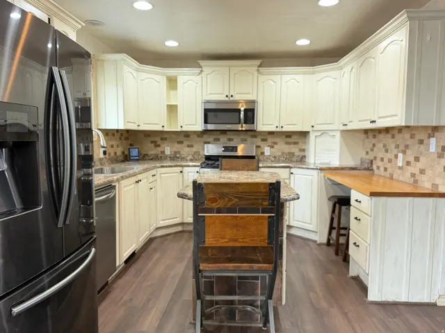 Kitchen featuring stainless steel appliances, dark wood finished floors, light stone counters, and recessed lighting