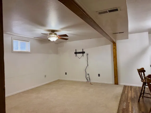 Basement featuring a ceiling fan and baseboards