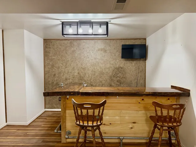 Indoor dry bar featuring butcher block counters and dark wood finished floors