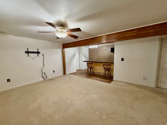 Finished basement featuring a bar, ceiling fan, and carpet flooring