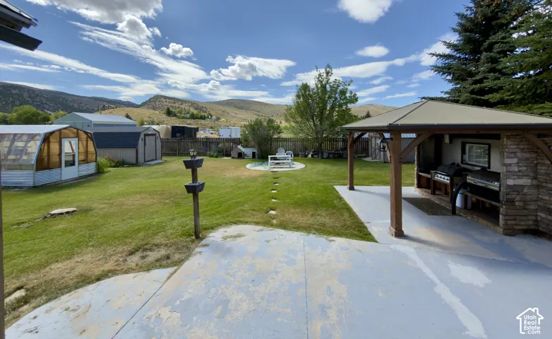 Expansive concrete patio with a covered outdoor kitchen featuring stacked stone accents and built-in appliances