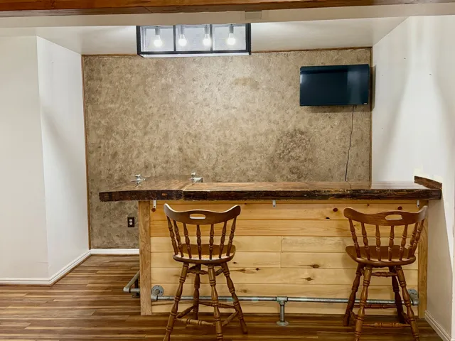 Indoor wet bar featuring dark wood-style flooring and an accent wall