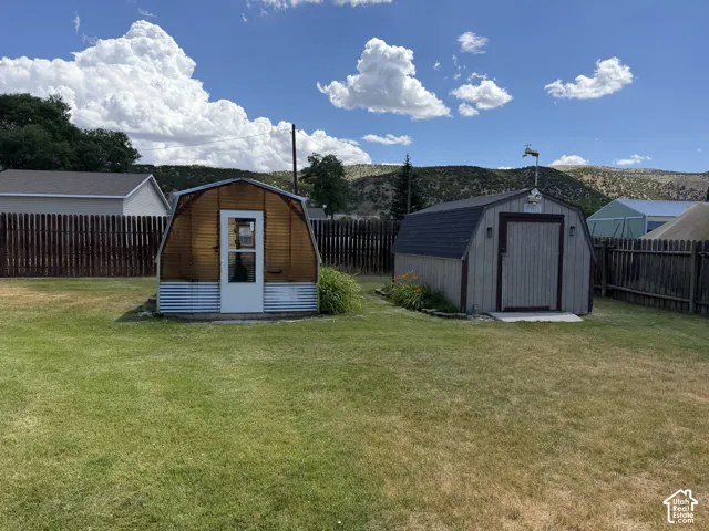Expansive lawn area with two storage sheds and wood fencing