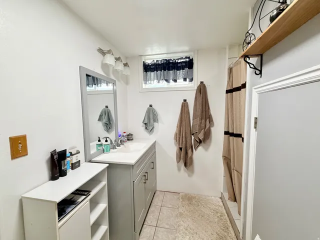 3/4 bath with a shower with curtain, vanity, and light tile patterned floors