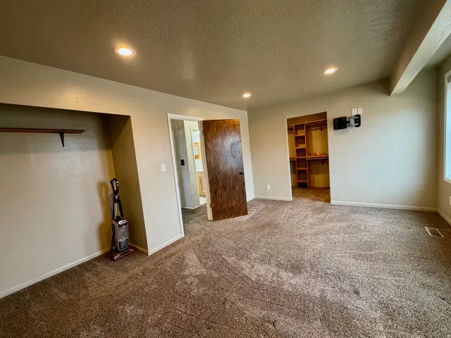 Unfurnished bedroom featuring a spacious closet, a textured ceiling, recessed lighting, and carpet flooring