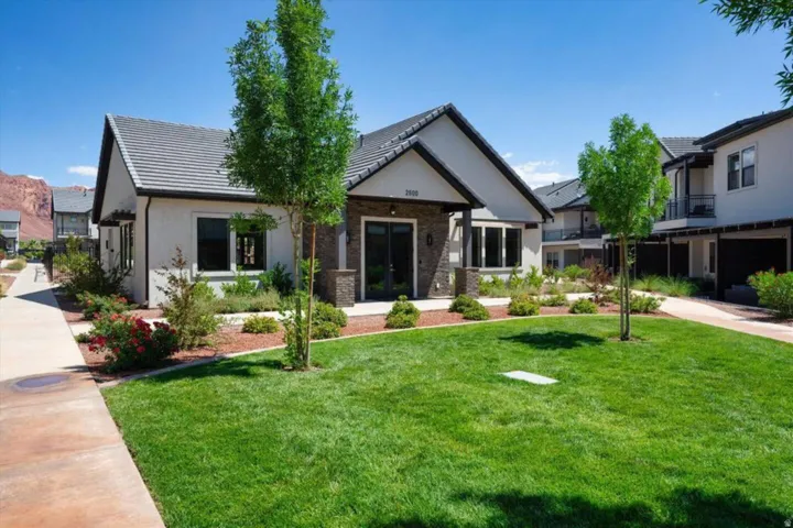 View of front facade featuring a front yard, stucco siding, brick siding, and a tile roof