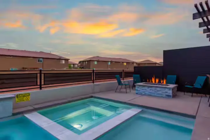 View of pool featuring an outdoor fire pit, a pool with connected hot tub, and a residential view