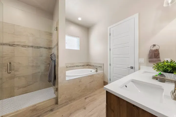 Full bath with a bath, a shower stall, double vanity, and light wood-style flooring
