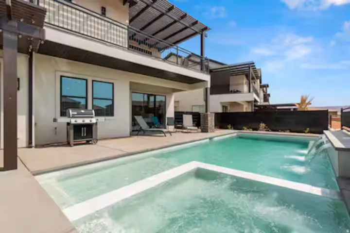 View of pool featuring a pool with connected hot tub, a grill, a patio area, and a balcony