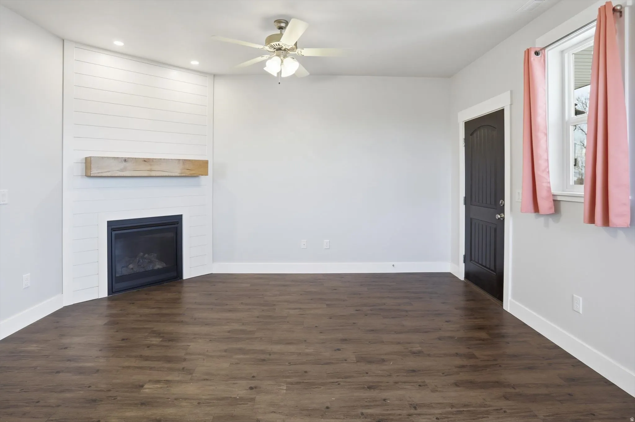 ADU living room with dark wood-style floors, a large fireplace, recessed lighting, and a ceiling fan