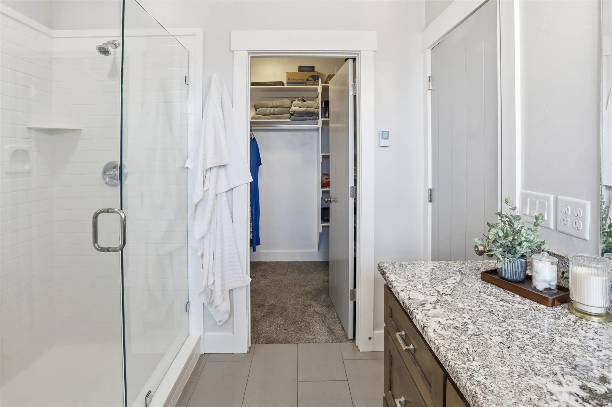 Ensuite primary Full bath featuring vanity, a spacious closet, a tiled shower,  and light tile patterned flooring