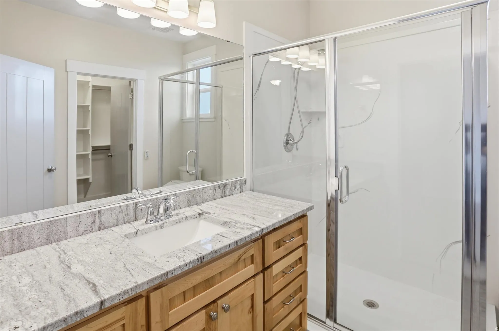 ADU Bathroom with vanity, a stall shower, and a spacious closet